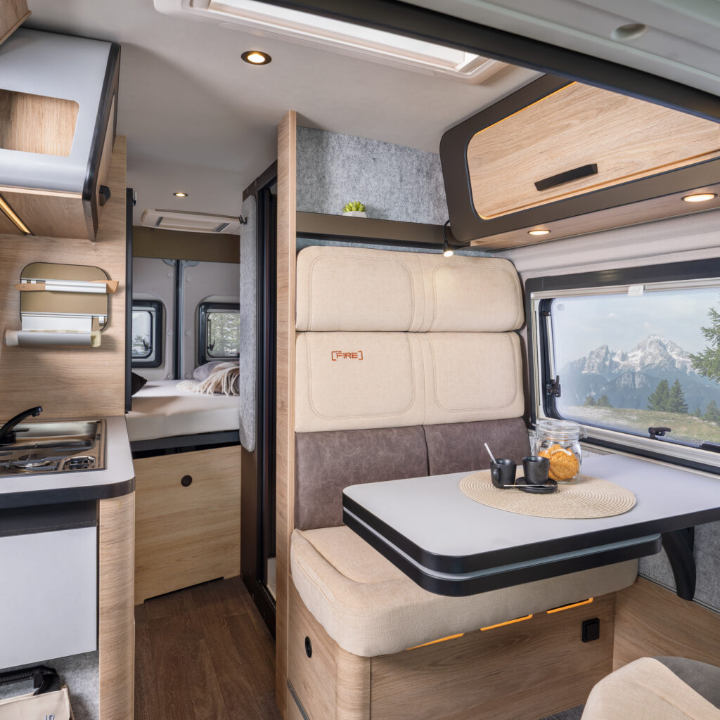 Interiör i en campervan med sittgrupp, matbord och kök
